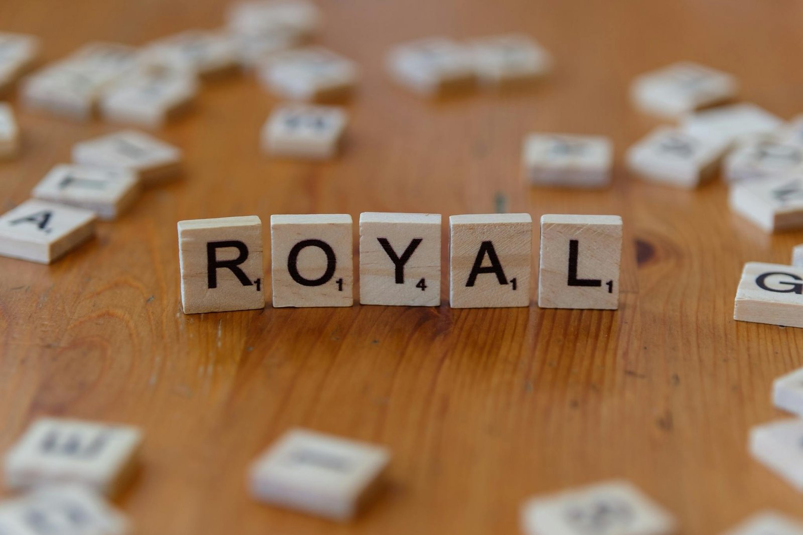 Scrabble tiles lay on a wood table, spelling the word 'Royal' in a playful setting.