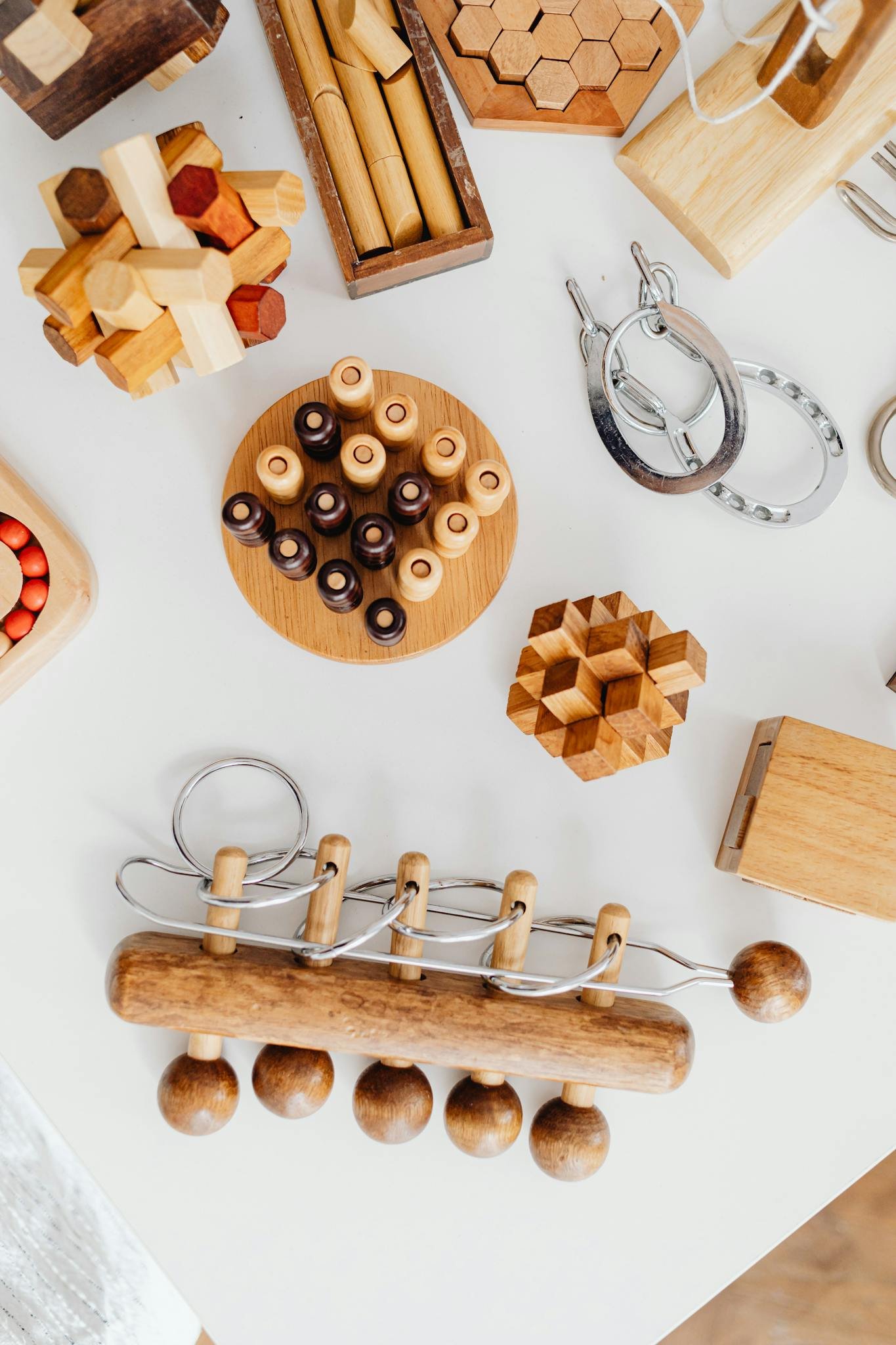 Top view of various wooden puzzles and brain teasers on a white table.